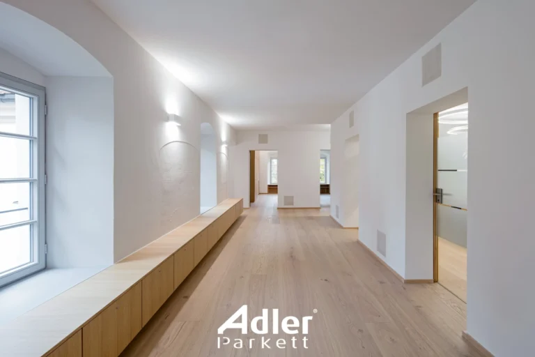 Heller, langer Flur mit Adler Parkett "Château Eiche swiss". Integrierte Holzbank und Schränke entlang der Wand.