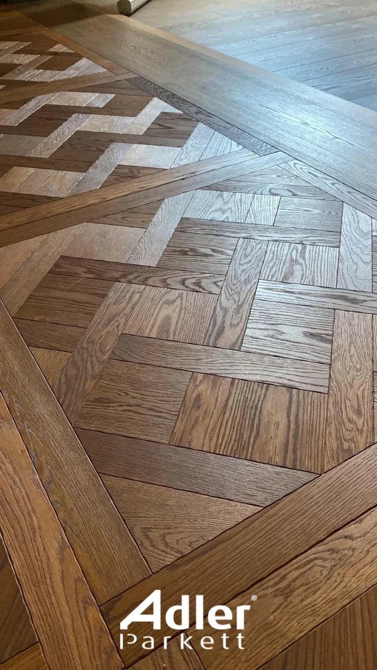 Nahaufnahme eines kunstvollen Adler Parkett Bodens mit verschiedenen Holzmaserungen und einem geometrischen Muster.