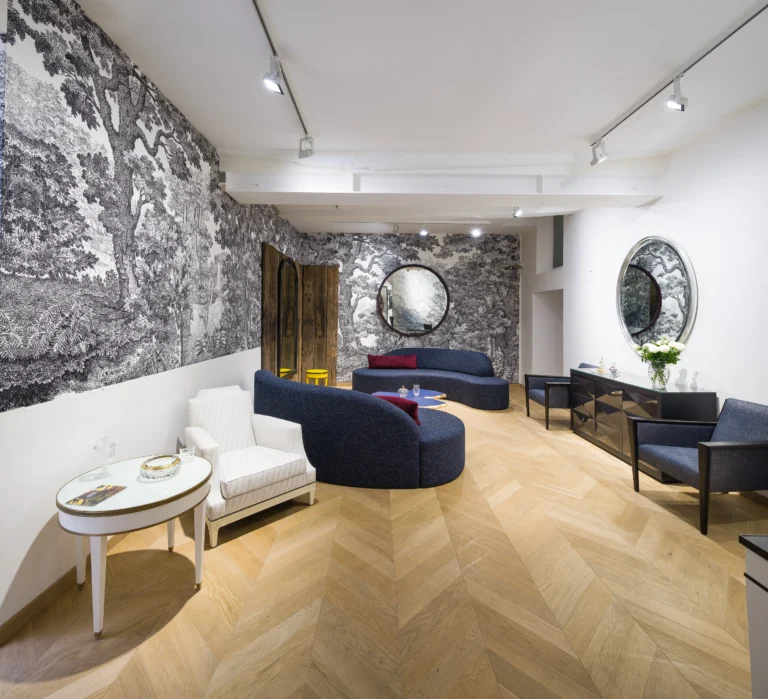 Wohnzimmer mit hellem Point de Hongrie Parkett und auffälliger schwarz-weißer Waldtapete. Blaue geschwungene Sofas und Sessel.