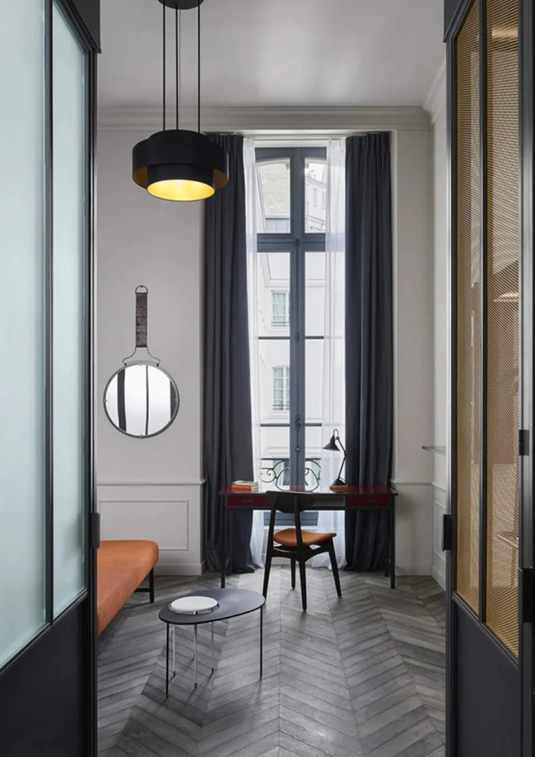 Eleganter Flur mit dunkelgrauem Point de Hongrie Parkett. Ein Schreibtisch am Fenster, ein Hängespiegel und dunkle Vorhänge.