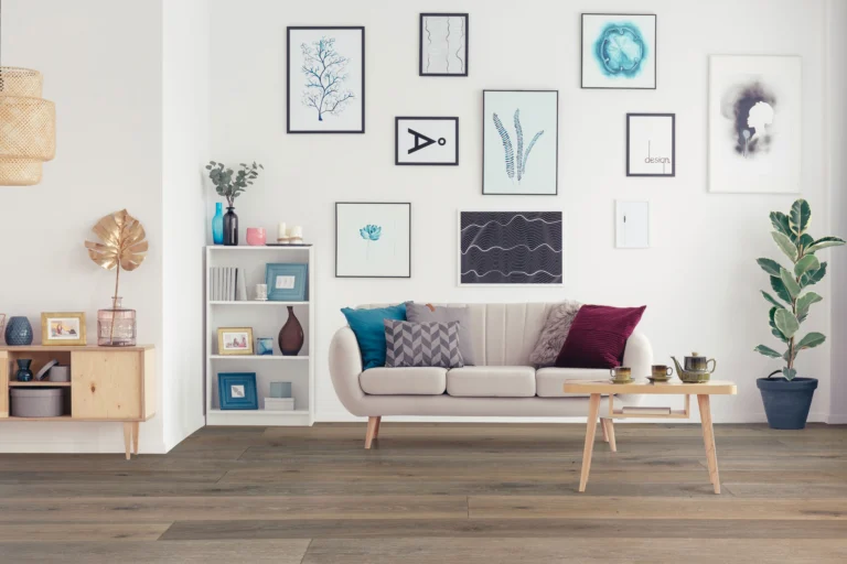 Modernes Wohnzimmer mit hellem Holzdielenboden. Ein beiges Sofa, ein Couchtisch und eine Galeriewand mit verschiedenen Bildern.